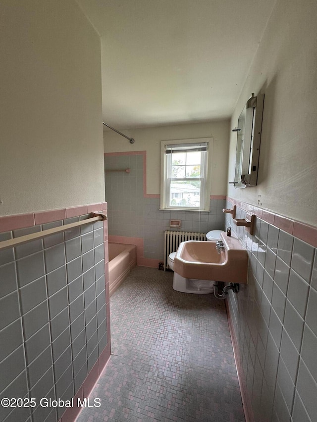 46 Elmhurst Ave, Albany, NY 12203 - bathroom featuring tile walls, radiator heating unit, a wainscoted wall, toilet, and a sink
