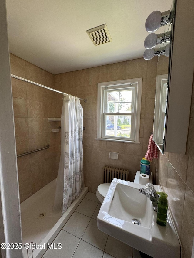 46 Elmhurst Ave, Albany, NY 12203 - bathroom featuring radiator, tile walls, a stall shower, tile patterned flooring, and toilet