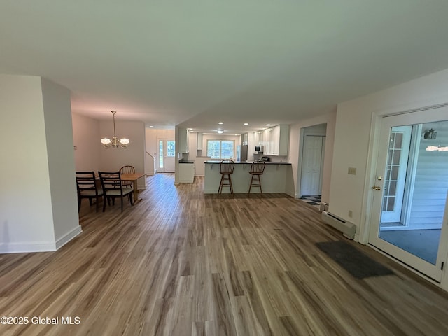 12 Graves St, Glens Falls, NY 12801 - living area with baseboard heating, a chandelier, wood finished floors, baseboards, and recessed lighting