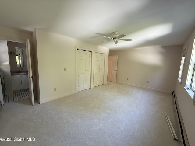 12 Graves St, Glens Falls, NY 12801 - unfurnished bedroom with a baseboard radiator, two closets, light colored carpet, a sink, and baseboards
