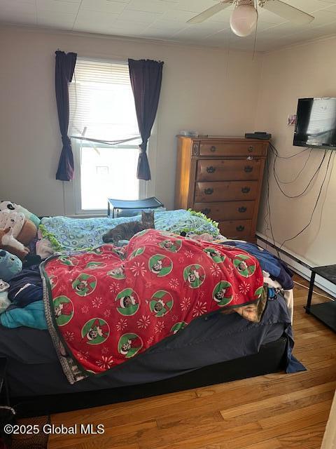 159 Champlain Ave, Ticonderoga, NY 12883 - bedroom with wood finished floors, a ceiling fan, a baseboard heating unit, and crown molding