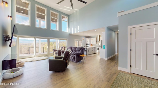 74 Dick Hyatt Ln, Whitehall, NY 12887 - living room with a high ceiling, a ceiling fan, light wood finished floors, and baseboards