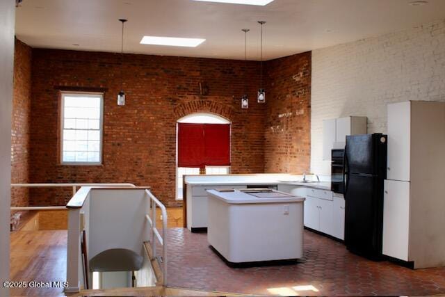 7 Garden Aly, Albany, NY 12210 - kitchen with black appliances, a center island, white cabinets, brick wall, and hanging light fixtures