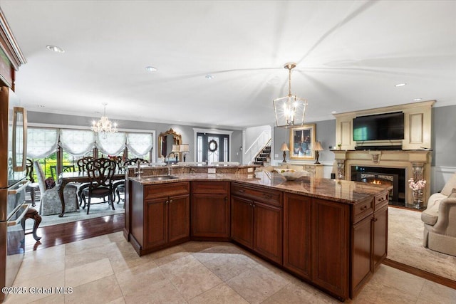1335 Stanley Ln, Niskayuna, NY 12309 - kitchen featuring open floor plan, a chandelier, a sink, a glass covered fireplace, and stone countertops