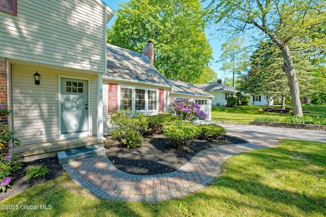 9 S Maple Ln, Colonie, NY 12211 - property entrance featuring a chimney, a yard, and a shingled roof