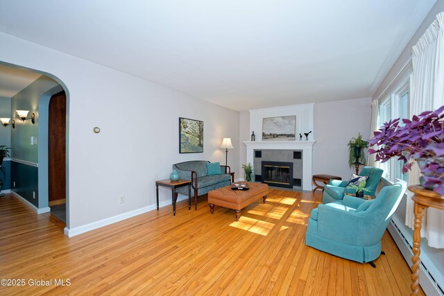 9 S Maple Ln, Colonie, NY 12211 - living room featuring a fireplace with flush hearth, light wood-style floors, arched walkways, and baseboard heating