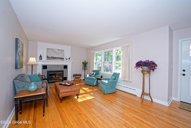 9 S Maple Ln, Colonie, NY 12211 - living room with a baseboard heating unit, light wood-style flooring, a glass covered fireplace, and baseboards