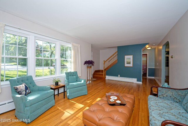 9 S Maple Ln, Colonie, NY 12211 - living room featuring a baseboard radiator, wood finished floors, stairway, and arched walkways