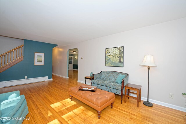 9 S Maple Ln, Colonie, NY 12211 - living room featuring baseboard heating, arched walkways, stairway, wood finished floors, and baseboards