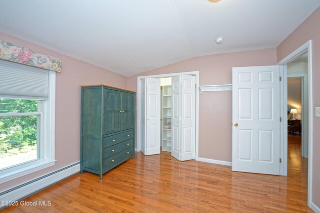 9 S Maple Ln, Colonie, NY 12211 - unfurnished bedroom with a baseboard radiator, light wood-style flooring, vaulted ceiling, a closet, and baseboards
