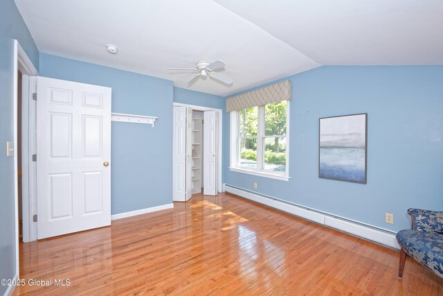 9 S Maple Ln, Colonie, NY 12211 - unfurnished bedroom with a baseboard radiator, wood finished floors, baseboards, a closet, and vaulted ceiling