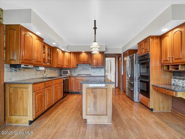 3077 New Williamsburg Dr, Guilderland, NY 12303 - kitchen featuring appliances with stainless steel finishes, a center island, light wood-style floors, brown cabinets, and backsplash
