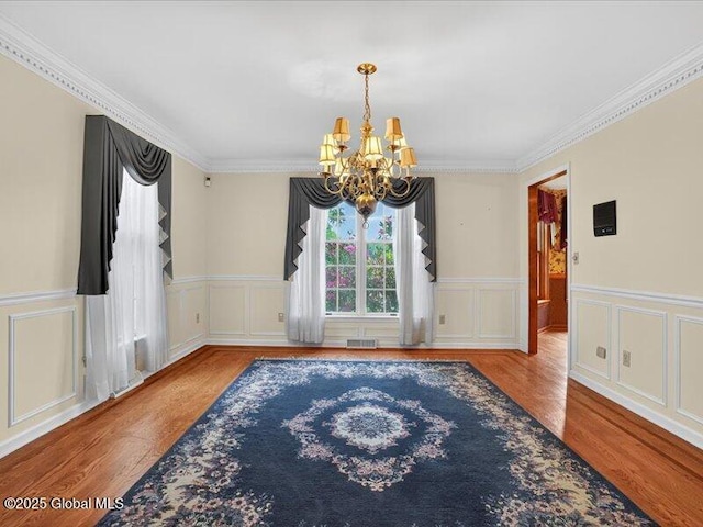 3077 New Williamsburg Dr, Guilderland, NY 12303 - empty room with a chandelier, wood finished floors, crown molding, a decorative wall, and a wainscoted wall
