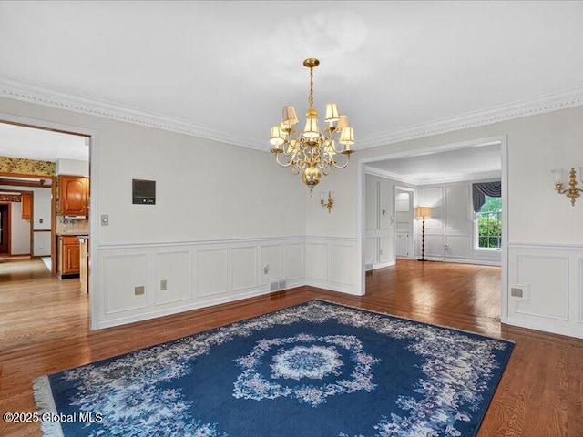 3077 New Williamsburg Dr, Guilderland, NY 12303 - dining space featuring a chandelier, wood finished floors, ornamental molding, a decorative wall, and a wainscoted wall