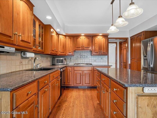 3077 New Williamsburg Dr, Guilderland, NY 12303 - kitchen with stainless steel appliances, wood finished floors, brown cabinets, dark stone counters, and glass insert cabinets