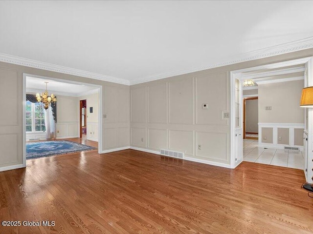 3077 New Williamsburg Dr, Guilderland, NY 12303 - unfurnished living room with a decorative wall, a chandelier, light wood-style flooring, and crown molding