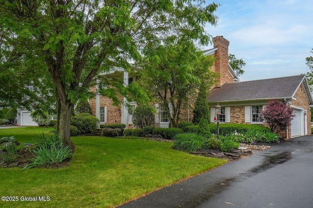 3077 New Williamsburg Dr, Guilderland, NY 12303 - view of property hidden behind natural elements featuring a front lawn, a chimney, brick siding, and an attached garage