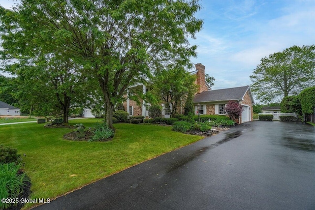3077 New Williamsburg Dr, Guilderland, NY 12303 - view of front of house with asphalt driveway, a front lawn, a chimney, and brick siding
