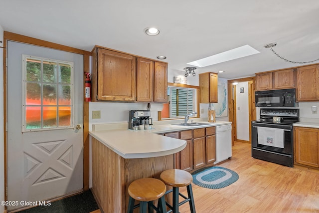 858 E River Dr, Lake Luzerne, NY 12846 - kitchen with black appliances, a sink, a skylight, light countertops, and light wood-style floors