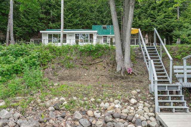 858 E River Dr, Lake Luzerne, NY 12846 - view of front facade featuring stairs, metal roof, and a wooded view
