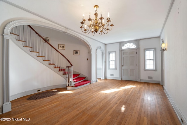 2125 Rosendale Rd, Niskayuna, NY 12309 - entrance foyer featuring wood-type flooring, a chandelier, stairs, arched walkways, and baseboards