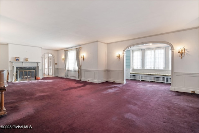 2125 Rosendale Rd, Niskayuna, NY 12309 - unfurnished living room featuring radiator heating unit, a decorative wall, arched walkways, carpet, and crown molding
