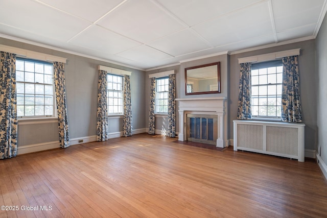 2125 Rosendale Rd, Niskayuna, NY 12309 - unfurnished living room featuring radiator, light wood finished floors, ornamental molding, a fireplace with flush hearth, and healthy amount of natural light