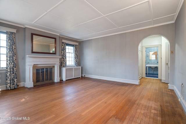 2125 Rosendale Rd, Niskayuna, NY 12309 - unfurnished living room featuring radiator heating unit, light wood-style floors, a fireplace with flush hearth, arched walkways, and baseboards