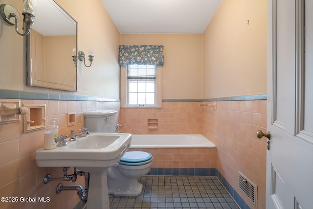 2125 Rosendale Rd, Niskayuna, NY 12309 - full bathroom featuring toilet, tile walls, a wainscoted wall, a bath, and tile patterned flooring