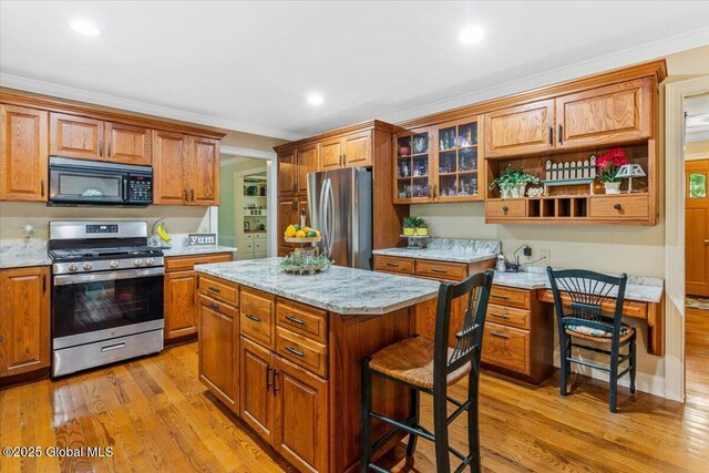 19 Canterbury Rd, Clifton Park, NY 12065 - kitchen with stainless steel appliances, a kitchen bar, ornamental molding, light wood-style flooring, and brown cabinets