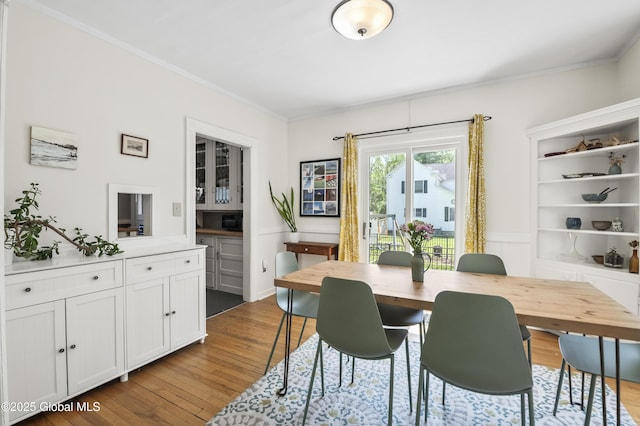30 Monument Ave, Glens Falls, NY 12801 - dining space with dark wood finished floors, crown molding, a wainscoted wall, and a decorative wall