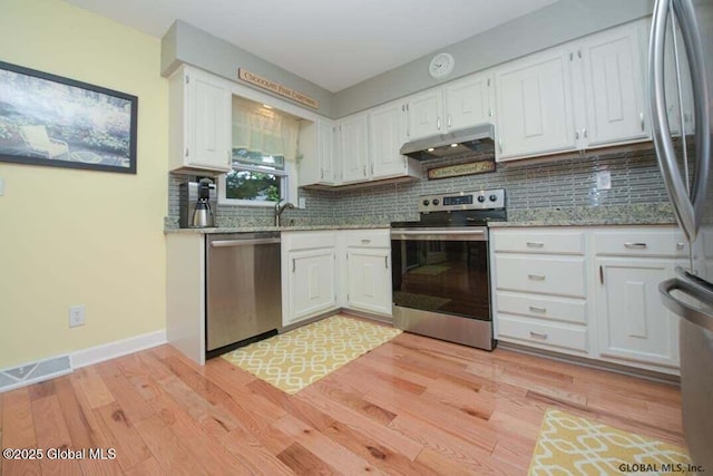 198 Williamsburg Ct, Albany, NY 12203 - kitchen with appliances with stainless steel finishes, under cabinet range hood, white cabinets, decorative backsplash, and light wood-style floors