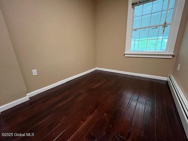 201 10th St, Troy, NY 12180 - empty room featuring a baseboard radiator, dark wood-style floors, and baseboards