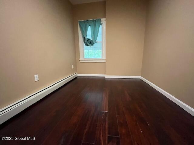 201 10th St, Troy, NY 12180 - empty room with a baseboard heating unit, dark wood-style floors, and baseboards