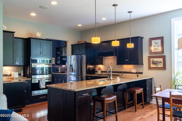 26 Galleon Dr Unit 26, Malta, NY 12020 - kitchen featuring stainless steel appliances, backsplash, light wood-style floors, a breakfast bar, and light stone countertops