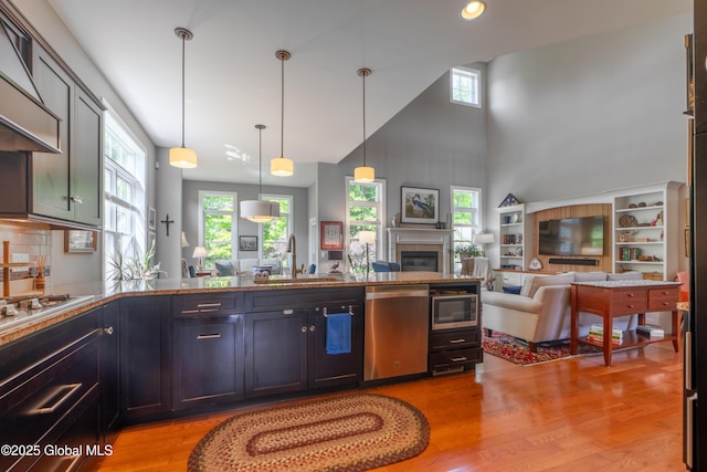 26 Galleon Dr Unit 26, Malta, NY 12020 - kitchen featuring appliances with stainless steel finishes, range hood, a sink, open floor plan, and light wood-style flooring