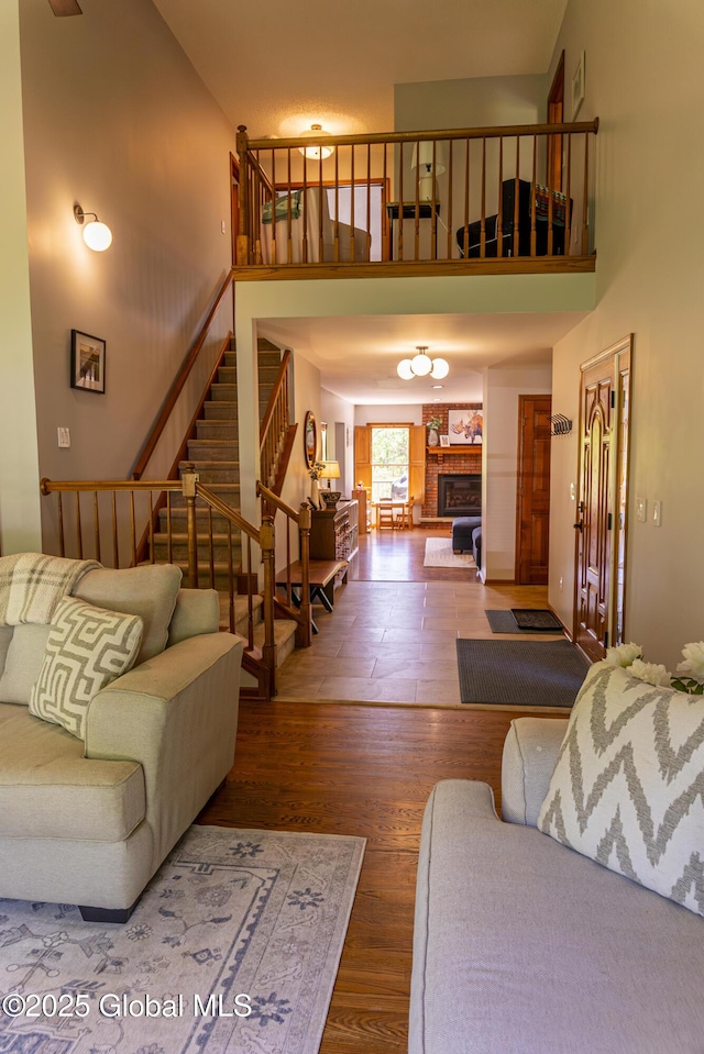 844 Red Oak Dr, Niskayuna, NY 12309 - living area with wood finished floors, stairs, a fireplace with raised hearth, and a high ceiling