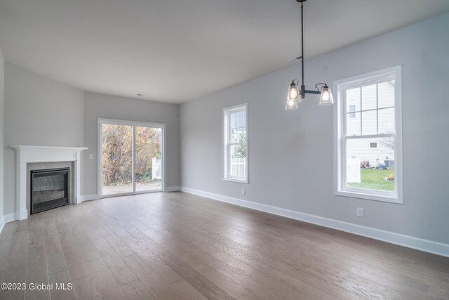 16 Priddle Ln, Colonie, NY 12110 - unfurnished living room with wood finished floors, baseboards, a glass covered fireplace, and a chandelier