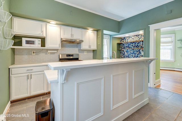 1348 Union St, Schenectady, NY 12308 - kitchen with white cabinets, under cabinet range hood, tasteful backsplash, light countertops, and light tile patterned floors