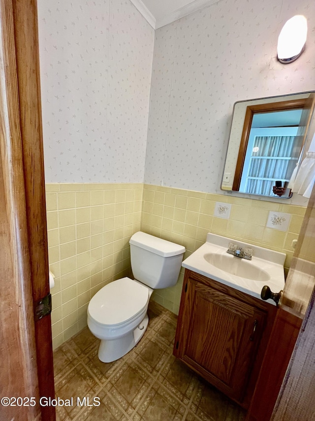 19 Lillian Dr, Glenville, NY 12302 - bathroom featuring wallpapered walls, toilet, vanity, tile walls, and wainscoting