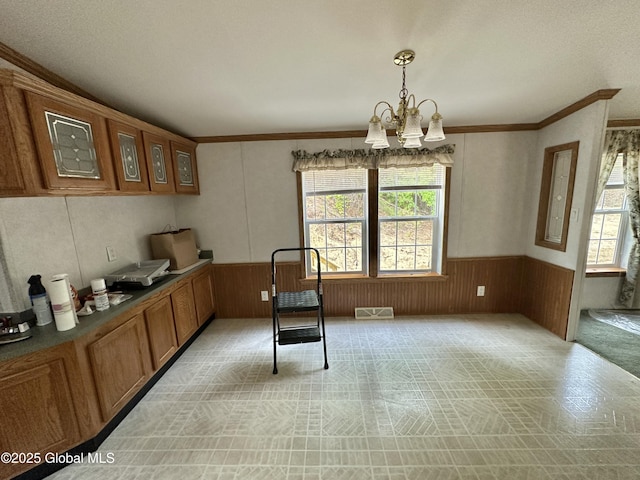 6041 Rte 9n, Hadley, NY 12835 - kitchen featuring plenty of natural light, brown cabinetry, wainscoting, a chandelier, and wood walls