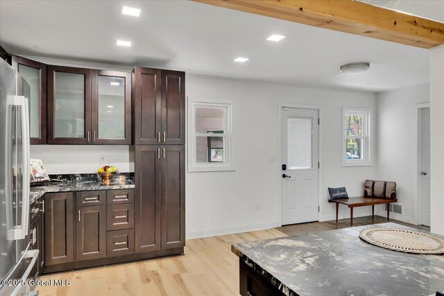 55 Fairview Ave, Hudson, NY 12534 - kitchen featuring light wood-type flooring, stainless steel refrigerator, dark brown cabinetry, glass insert cabinets, and dark stone countertops