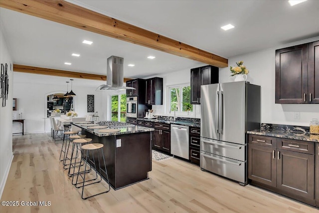 55 Fairview Ave, Hudson, NY 12534 - kitchen featuring appliances with stainless steel finishes, island exhaust hood, light wood-style floors, dark stone counters, and a breakfast bar