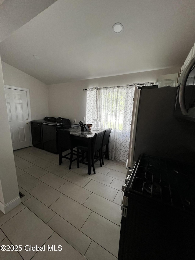 94 Willow Ave, Schenectady, NY 12304 - dining area featuring washer and dryer, light tile patterned flooring, and vaulted ceiling