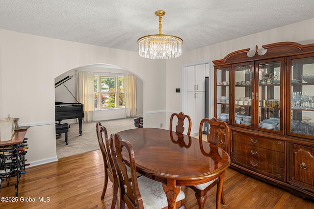 228 Vincenza Ln, Guilderland, NY 12303 - dining room featuring arched walkways, a textured ceiling, a chandelier, and wood finished floors