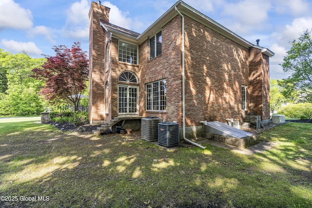 17 Brendan Ln, Niskayuna, NY 12309 - back of house with brick siding, central air condition unit, a chimney, and a lawn
