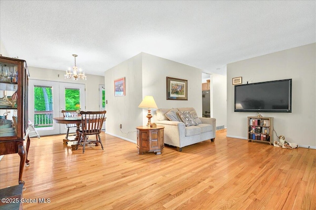 3 N Jordan Dr, Saratoga Springs, NY 12866 - living room with light wood finished floors, a chandelier, and a textured ceiling