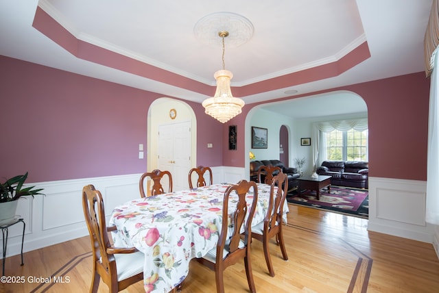 1 Avalon Ct, Colonie, NY 12211 - dining space with arched walkways, wainscoting, light wood finished floors, a chandelier, and a raised ceiling