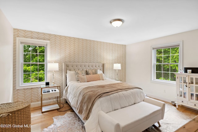 151 Edie Rd, Wilton, NY 12866 - bedroom with wallpapered walls, baseboards, an accent wall, multiple windows, and light wood-style flooring