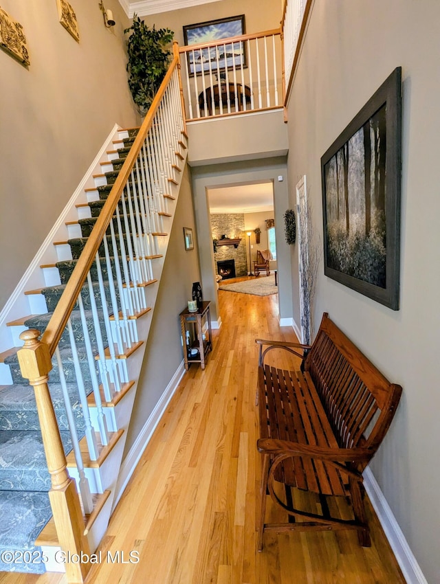 181 Fieldstone Dr, Niskayuna, NY 12304 - stairs featuring wood finished floors, a high ceiling, baseboards, and a warm lit fireplace